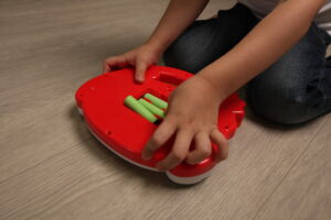 baby inserts batteries into a child's toy. child is dangerous playing with batteries
