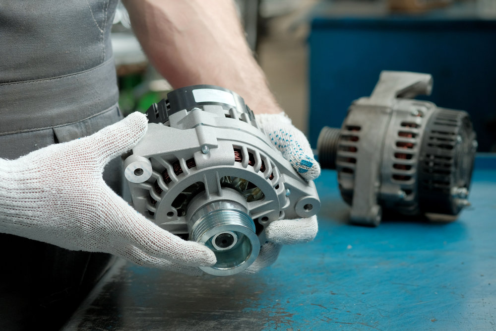 Car service.The generator is new in the hands of an auto mechanic. There is an old faulty generator nearby on the desktop.Inspection and control of the integrity of the spare part.