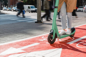 traffic, city transport and people concept - woman riding electric scooter along red bike lane with signs of bicycles and two way arrows on street