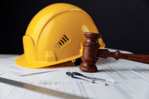 Wooden gavel with yellow helmet. Construction law concept.