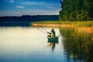 father and son catch fish from a boat at sunset