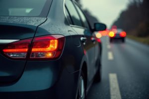 Several cars are involved in a traffic accident on a rainy road during dusk. Emergency responders are present, assisting with the situation and managing traffic.